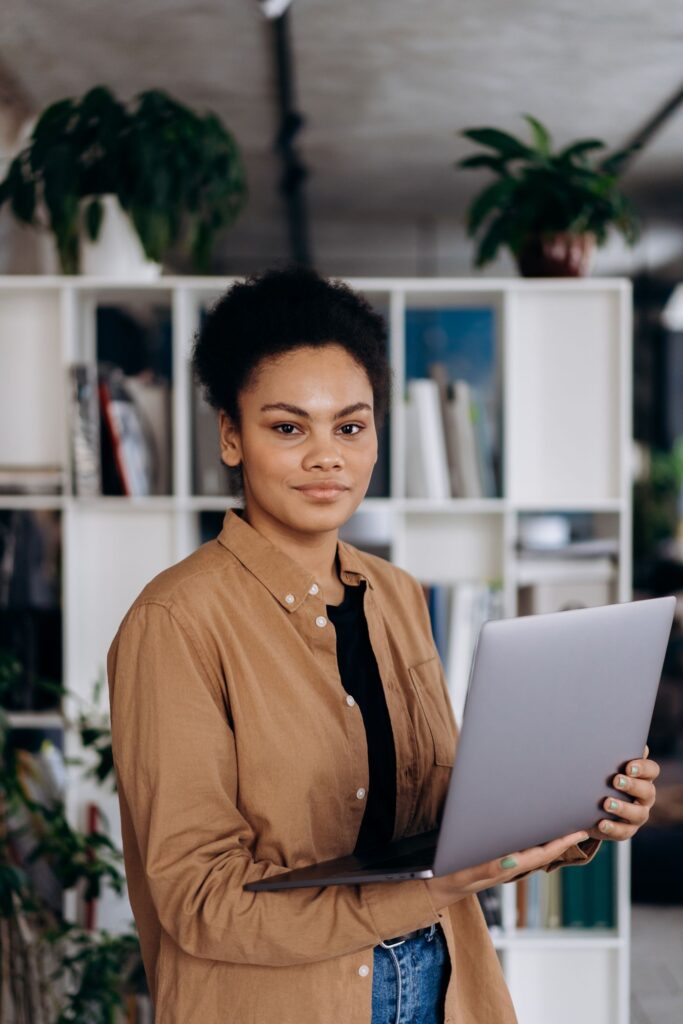 A professional holding her laptop in a bright office